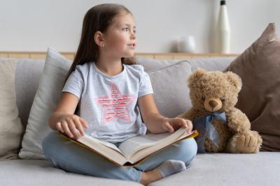 Kind mit Buch und Teddy